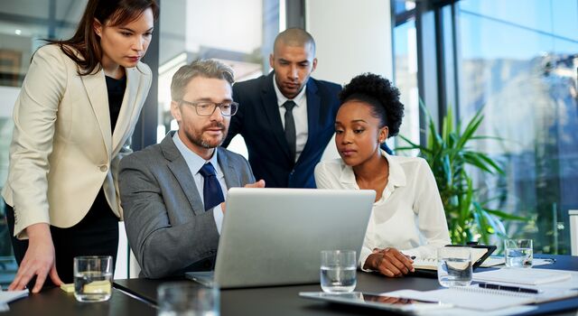 COLOUR-IMAGE_four-professionals-discussing-over-one-laptop-screen_jul26