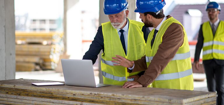 COLOUR-IMAGE_two-workers_construction_site_laptop_july26