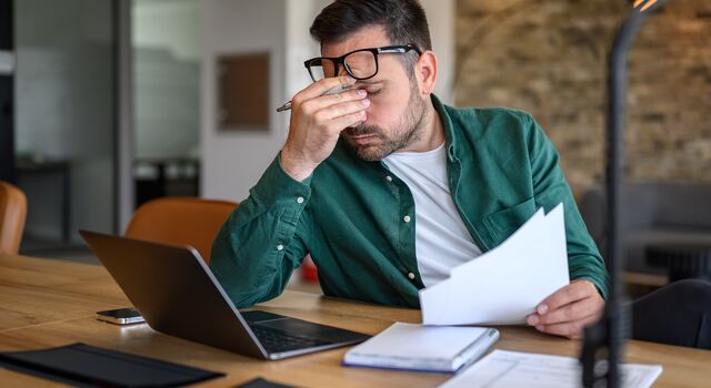 COLOUR-IMAGE_Male-rubbing-eyes-working over-laptop_july26