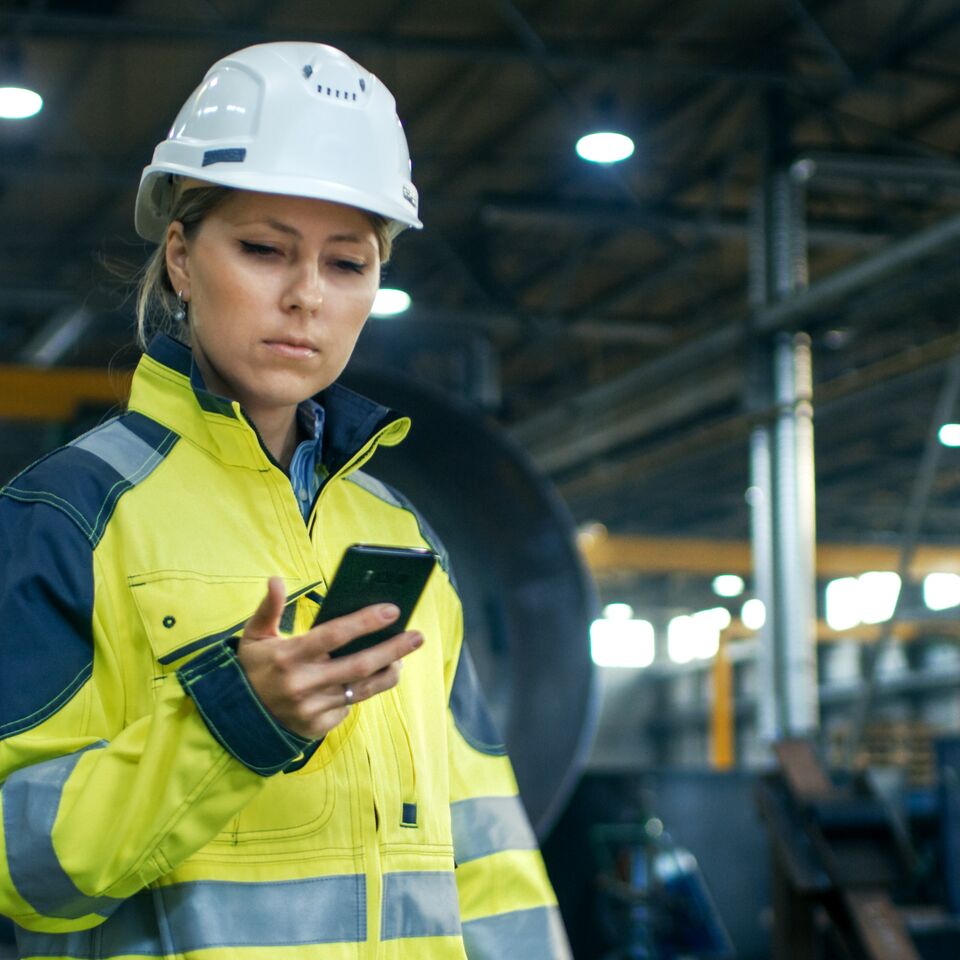 COLOUR-IMAGE_female-worker-in-hi-vis-looking-at-mobile-phone_jul26