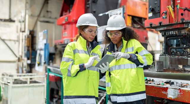 COLOUR-IMAGE_two-ladies-in-hi-vis-and-hard-hats-discussing-outside-of-factory_apr26
