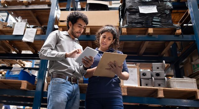 COLOUR-IMAGE_man-and-woman-in-factory-looking-at-tablet-and-clipboard_apr26
