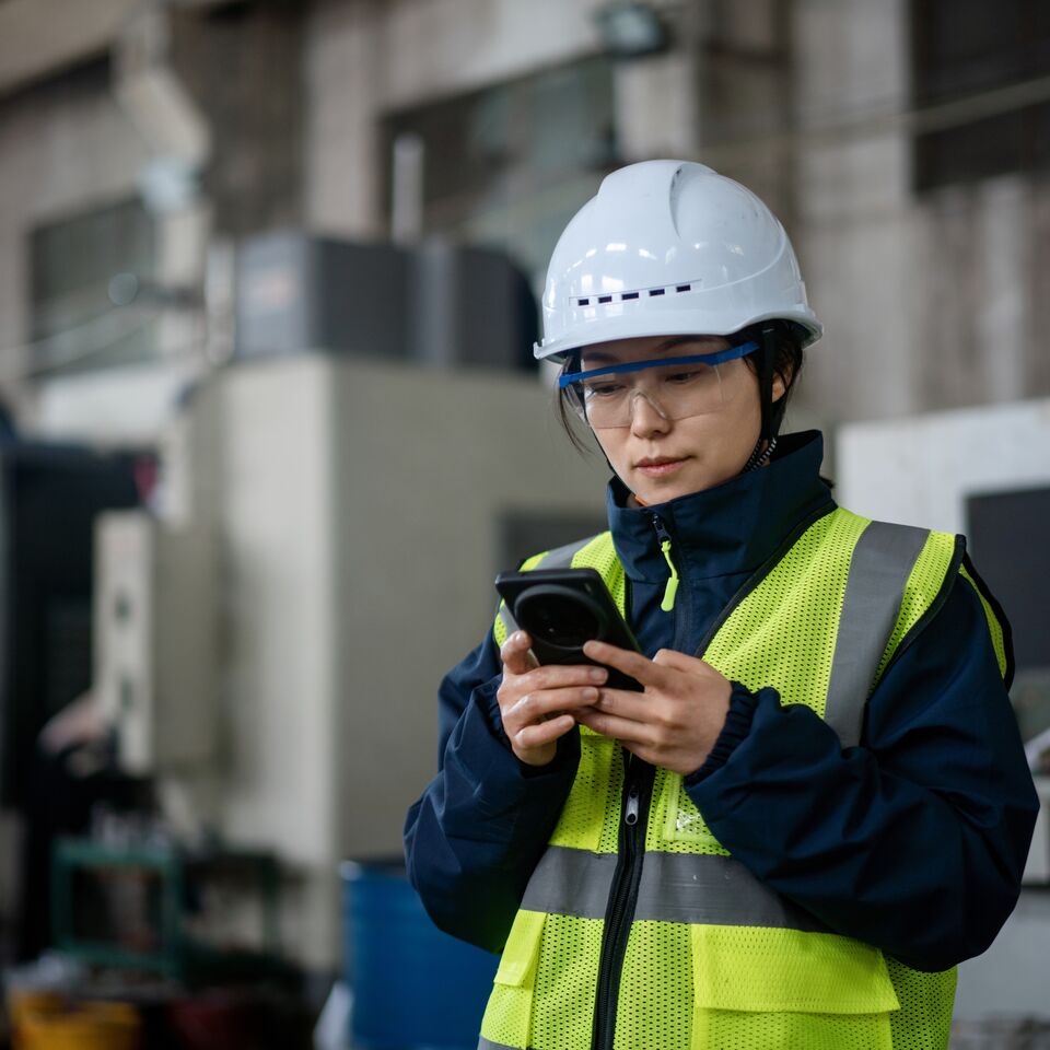 COLOUR-IMAGE_female-worker-EHS-hi-vis-looking-at-mobile-phone_jul26