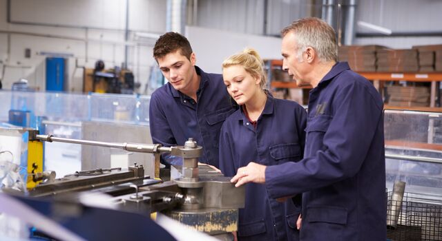 COLOUR-IMAGE_three-employees-in-factory-wearing-blue-jumpsuits_apr26